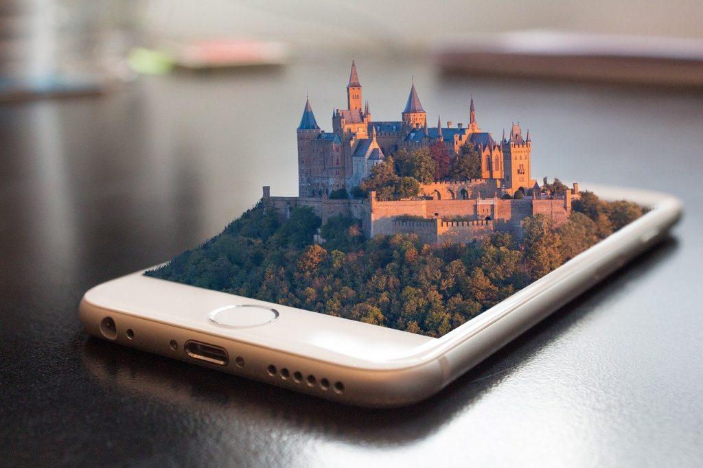 Téléphone portable duquel sort un château et une forêt